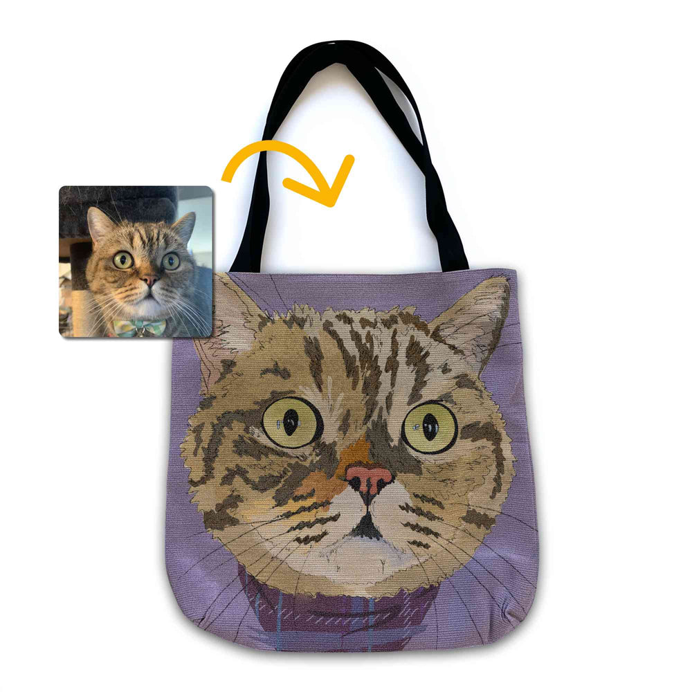 A woven tote bag with black shoulder straps featuring a custom illustrated cat portrait of a tabby cat wearing a plaid bandana set against a subtle textured lavender background printed on the side of the bag, shown on a clean white background. A small inset photo of the cat appears in the upper left with a yellow arrow pointing to the bag design, indicating the custom design was drawn from the photo.