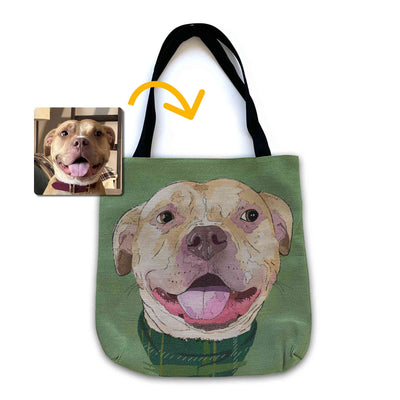 A woven tote bag with black shoulder straps featuring a custom illustrated dog portrait of a smiling tan dog wearing a plaid bandana set against a subtle textured green background printed on the side of the bag, shown on a clean white background. A small inset photo of the dog appears in the upper left with a yellow arrow pointing to the bag design, indicating the custom design was drawn from the photo.