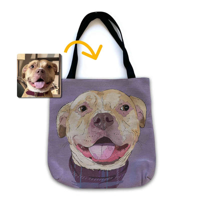 A woven tote bag with black shoulder straps featuring a custom illustrated dog portrait of a smiling tan dog wearing a plaid bandana set against a subtle textured lavender background printed on the side of the bag, shown on a clean white background. A small inset photo of the dog appears in the upper left with a yellow arrow pointing to the bag design, indicating the custom design was drawn from the photo.