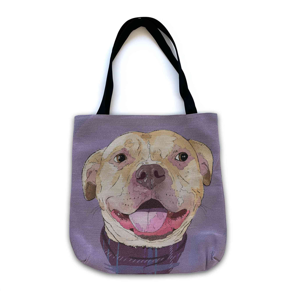 A woven tote bag with black shoulder straps featuring a custom illustrated dog portrait of a smiling tan dog wearing a plaid bandana set against a subtle textured lavender background printed on the side of the bag, shown on a clean white background. 