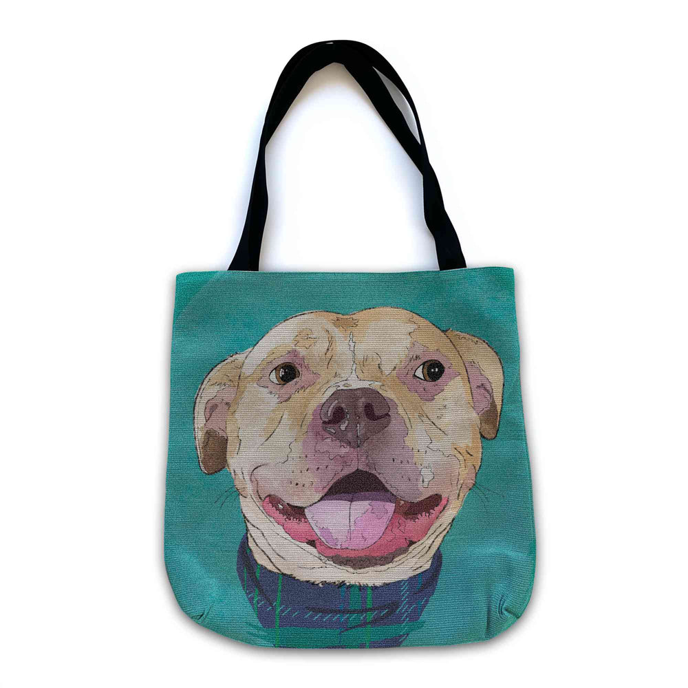 A woven tote bag with black shoulder straps featuring a custom illustrated dog portrait of a smiling tan dog wearing a plaid bandana set against a subtle textured teal background printed on the side of the bag, shown on a clean white background. 