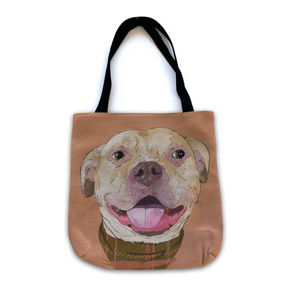 A woven tote bag with black shoulder straps featuring a custom illustrated dog portrait of a smiling tan dog wearing a plaid bandana set against a subtle textured orange background printed on the side of the bag, shown on a clean white background.